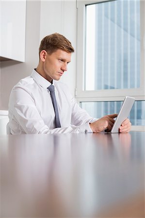 simsearch:693-07542313,k - Mid adult businessman using tablet computer at kitchen table Stock Photo - Premium Royalty-Free, Code: 693-07542225