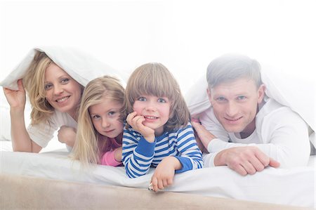 simsearch:640-06963757,k - Portrait of happy parents and children lying under bed cover Stock Photo - Premium Royalty-Free, Code: 693-07542258