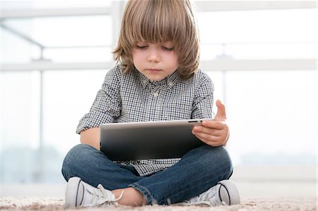 Full length of boy using digital tablet in living room Photographie de stock - Premium Libres de Droits, Code: 693-07542250