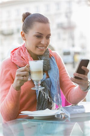 simsearch:693-07542313,k - Young woman having coffee while using cell phone at sidewalk cafe Stock Photo - Premium Royalty-Free, Code: 693-07542271