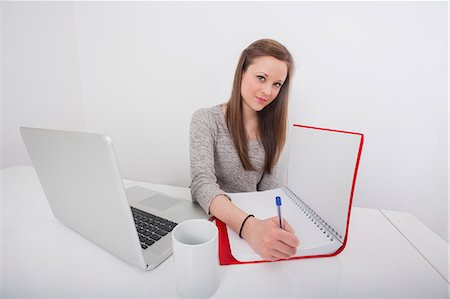 Portrait of beautiful businesswoman writing in book at office desk Stock Photo - Premium Royalty-Free, Code: 693-07542331