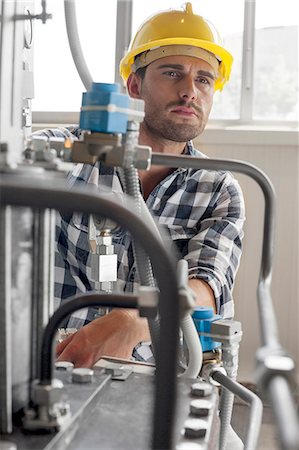 Manual worker looking away while examining machine in industry Stock Photo - Premium Royalty-Free, Code: 693-07672646