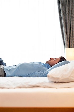 simsearch:693-07672717,k - Side view of young businessman sleeping on bed in hotel room Stock Photo - Premium Royalty-Free, Code: 693-07672664