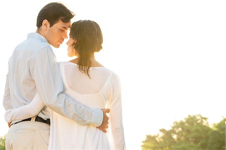 simsearch:693-07672684,k - Rear view of romantic couple standing arms around against clear sky Stock Photo - Premium Royalty-Free, Code: 693-07672757
