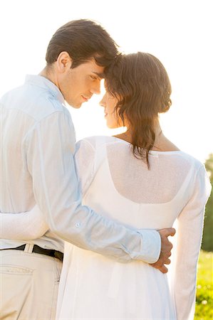 simsearch:693-07672684,k - Rear view of romantic couple standing arms around against clear sky Stock Photo - Premium Royalty-Free, Code: 693-07672758