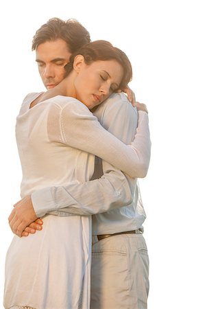 simsearch:693-07672684,k - Affectionate young couple with eyes closed hugging in park against clear sky Stock Photo - Premium Royalty-Free, Code: 693-07672762