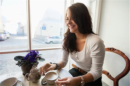 simsearch:693-07672977,k - Smiling young woman having coffee at cafe Photographie de stock - Premium Libres de Droits, Code: 693-07672974