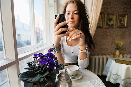 simsearch:693-07672977,k - Young woman using smart phone at cafe table Photographie de stock - Premium Libres de Droits, Code: 693-07672976