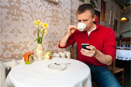 simsearch:693-07672977,k - Man having coffee while reading text message on cell phone at cafe Photographie de stock - Premium Libres de Droits, Code: 693-07672970