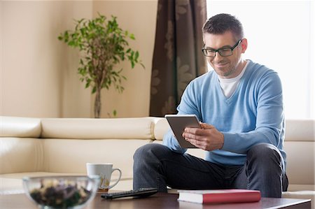 simsearch:693-07542313,k - Smiling man using tablet PC at home Stock Photo - Premium Royalty-Free, Code: 693-07673244