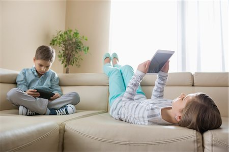 simsearch:693-07542313,k - Siblings using technologies on sofa at home Stock Photo - Premium Royalty-Free, Code: 693-07673263