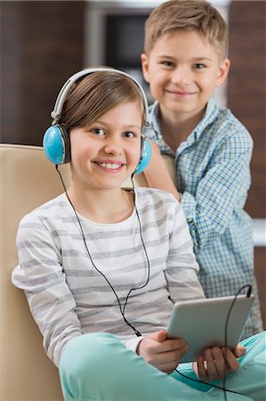 simsearch:693-07542313,k - Portrait of cute girl listening music on digital tablet while brother standing behind her Stock Photo - Premium Royalty-Free, Code: 693-07673276