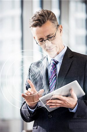 suit man eyeglasses - Middle aged businessman using digital tablet in office Stock Photo - Premium Royalty-Free, Code: 693-07673302