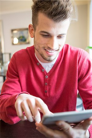 simsearch:693-07542313,k - Smiling young man using tablet PC in cafe Stock Photo - Premium Royalty-Free, Code: 693-07912169