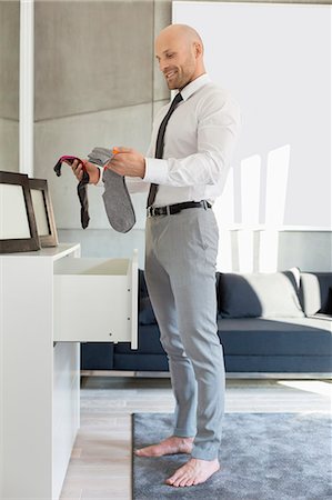 Full length side view of businessman selecting socks at home Stock Photo - Premium Royalty-Free, Code: 693-07912370