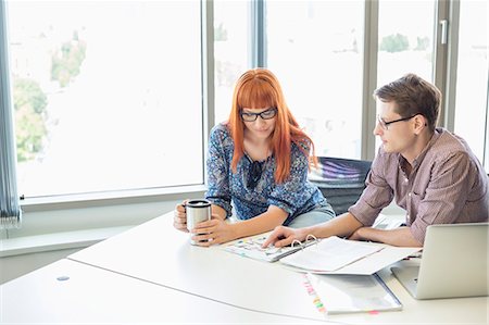 Creative business colleagues reading file together at desk in office Stock Photo - Premium Royalty-Free, Code: 693-07912533