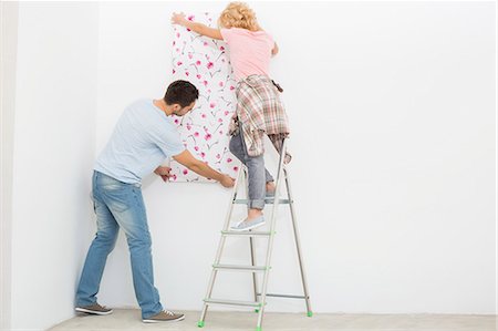 simsearch:693-07912629,k - Full-length rear view of couple applying wallpaper to wall Stock Photo - Premium Royalty-Free, Code: 693-07912584