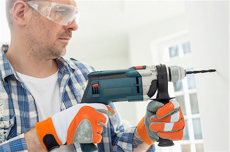 simsearch:693-07912629,k - Mid-adult man drilling hole in wall Stock Photo - Premium Royalty-Free, Code: 693-07912587