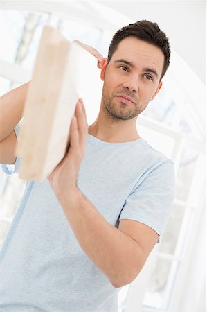 Mid-adult man carrying wooden plank on shoulder Photographie de stock - Premium Libres de Droits, Code: 693-07912617