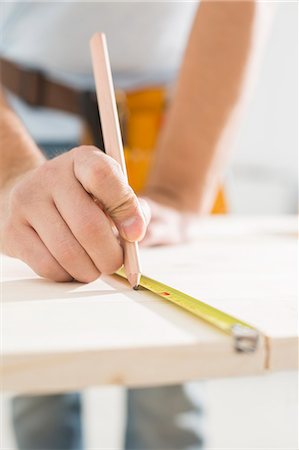 Midsection of carpenter marking table with measure tape Stock Photo - Premium Royalty-Free, Code: 693-07912610