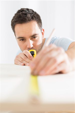 Mid-adult man marking table with measure tape Stock Photo - Premium Royalty-Free, Code: 693-07912612