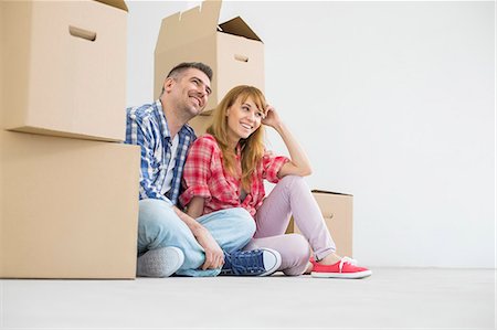 Full-length of happy couple sitting in new house Foto de stock - Sin royalties Premium, Código: 693-07912636