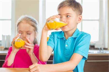 simsearch:6108-07969525,k - Siblings drinking orange juice in kitchen at home Stock Photo - Premium Royalty-Free, Code: 693-07912800