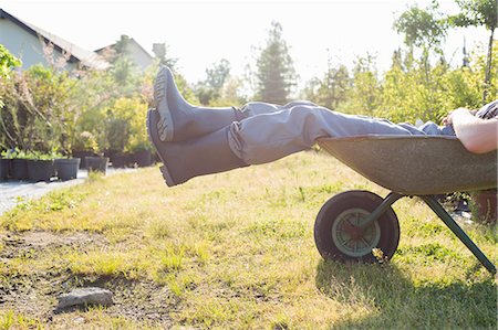 Low section of man relaxing in wheelbarrow at garden Stock Photo - Premium Royalty-Free, Code: 693-07912842