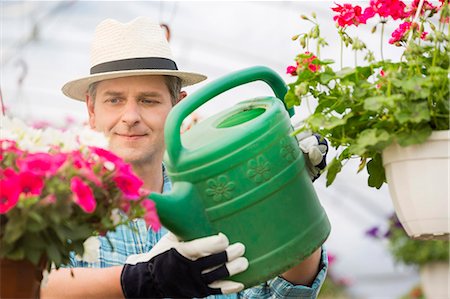 Middle-aged man watering flower plants in greenhouse Stock Photo - Premium Royalty-Free, Code: 693-07912861