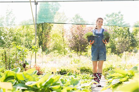 simsearch:649-07280682,k - Full-length of gardener looking away while holding potted plants at greenhouse Photographie de stock - Premium Libres de Droits, Code: 693-07912920