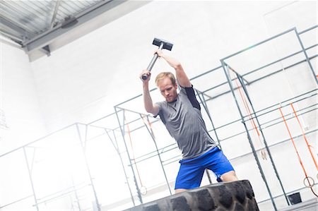simsearch:693-08126938,k - Man hitting tire with sledgehammer in crossfit gym Stock Photo - Premium Royalty-Free, Code: 693-08126934