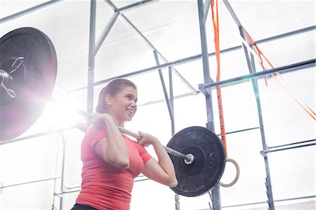 simsearch:693-08126938,k - Low angle view of smiling woman lifting barbell in crossfit gym Stock Photo - Premium Royalty-Free, Code: 693-08126942