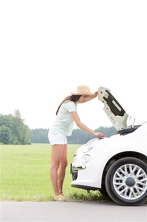 Side view of woman examining broken down car on country road Stock Photo - Premium Royalty-Free, Code: 693-08127091