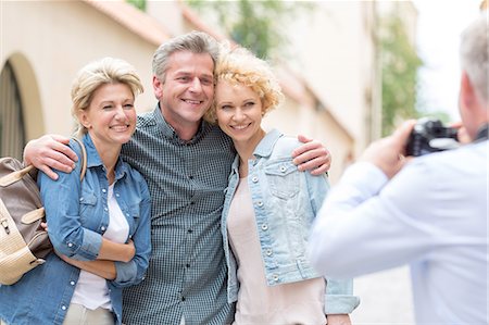 Rear view of man photographing male and female friends in city Stock Photo - Premium Royalty-Free, Code: 693-08127703