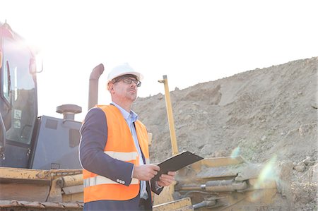 Engineer looking away while holding clipboard at construction site Stock Photo - Premium Royalty-Free, Code: 693-08127747