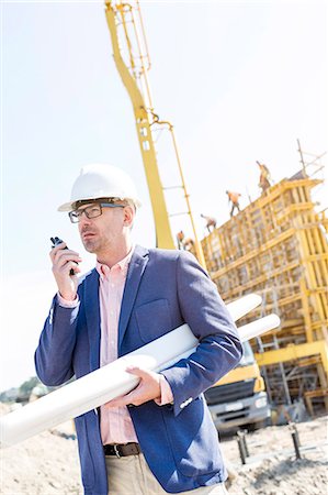 safety documents - Supervisor using walkie-talkie while holding blueprints at construction site Stock Photo - Premium Royalty-Free, Code: 693-08127799