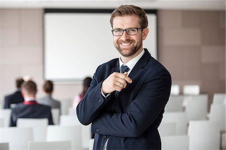Portrait of happy businessman standing in seminar hall Stock Photo - Premium Royalty-Free, Code: 693-08769471