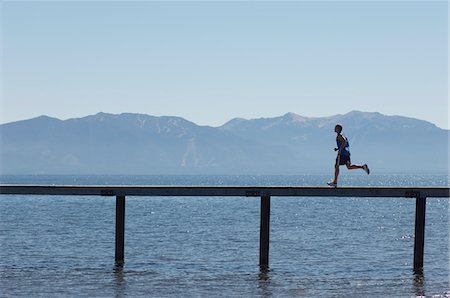 simsearch:400-04535435,k - Man running along pier with mountains behind, side view Stock Photo - Premium Royalty-Free, Code: 693-03299690