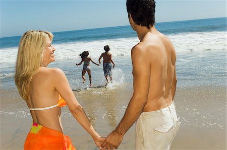 Parents watching children running into sea, holding hands Stock Photo - Premium Royalty-Free, Code: 693-03299739