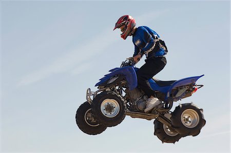 Man riding quad bike in mid-air against blue sky, close up Foto de stock - Sin royalties Premium, Código: 693-03299903