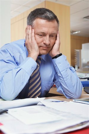 simsearch:400-04283915,k - Businessman sitting at desk with head in hands Stock Photo - Premium Royalty-Free, Code: 693-03305037