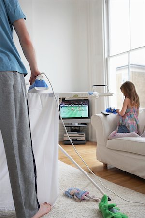 Woman ironing, (low section), daughter (5-6) playing on sofa Stock Photo - Premium Royalty-Free, Code: 693-03305065