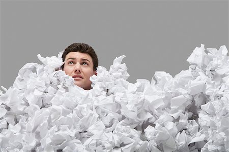 Adult man covered in crumpled paper, looking up Stock Photo - Premium Royalty-Free, Code: 693-03305252