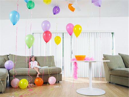 simsearch:693-03305634,k - Young girl (7-9) sitting in living room full of balloons Stock Photo - Premium Royalty-Free, Code: 693-03305624