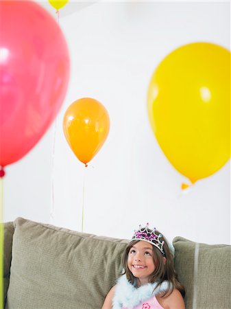 simsearch:693-03305634,k - Young girl (7-9) sitting on sofa looking at balloons Stock Photo - Premium Royalty-Free, Code: 693-03305625