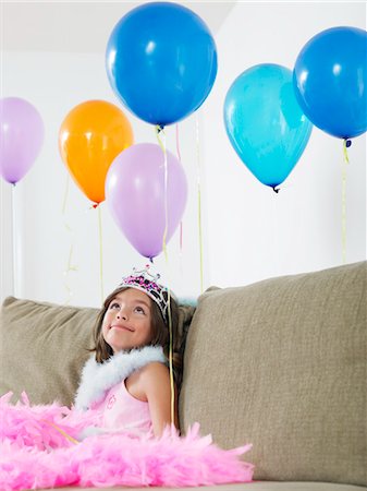 simsearch:693-03305634,k - Young girl (7-9) sitting on sofa looking at balloons Stock Photo - Premium Royalty-Free, Code: 693-03305626
