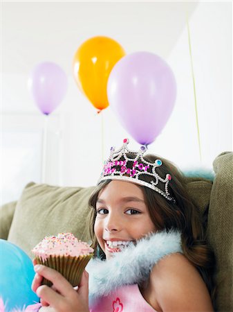 simsearch:693-03305634,k - Young girl (7-9) sitting on sofa eating cupcake, close-up Stock Photo - Premium Royalty-Free, Code: 693-03305628