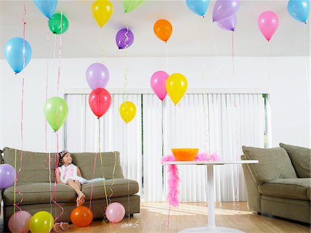 simsearch:693-03305634,k - Young girl (7-9) sitting in living room full of balloons Stock Photo - Premium Royalty-Free, Code: 693-03305623