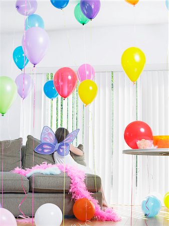 simsearch:693-03305634,k - Young girl (7-9) sitting on sofa with balloons, wearing fairy wings, back view Stock Photo - Premium Royalty-Free, Code: 693-03305638