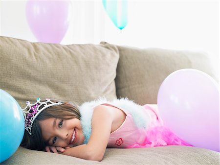 simsearch:693-03305634,k - Young girl (7-9) lying on sofa with balloons, smiling Stock Photo - Premium Royalty-Free, Code: 693-03305632